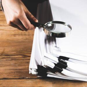 business woman holding magnifying glass and documents